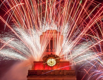 fireworks surround the top of the UT Tower which is lit with orange lights