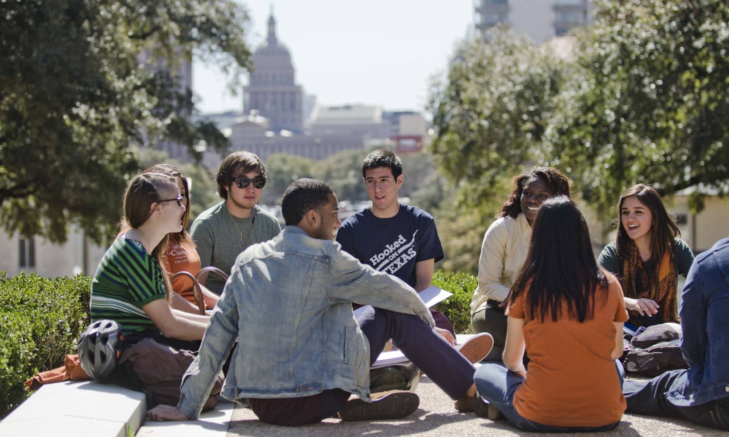 a group of students sitting in a circle outside with the Capital building in the distance
