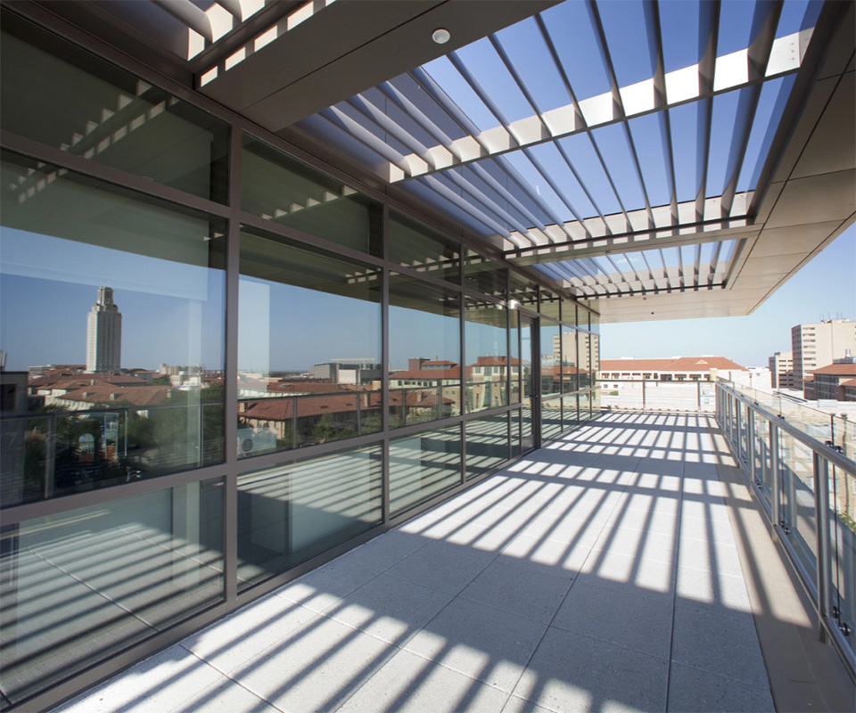 the view from a patio area looking over some campus buildings with windows reflecting additional campus buildings