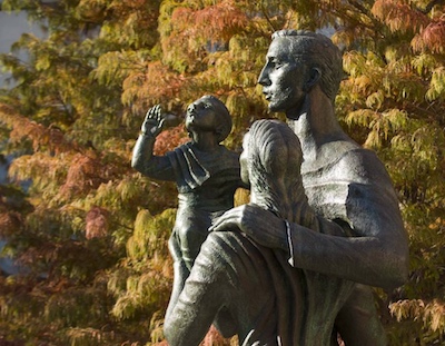 a bronze statue depicting three figures who look like a father, mother, and young child